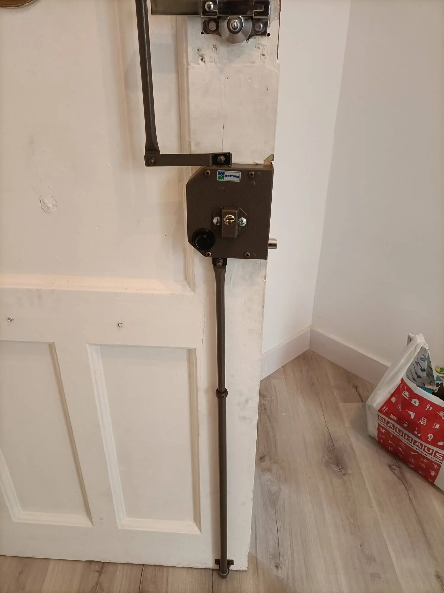 Cerradura de sobreponer Mottura con sistema de barras multipunto instalada en puerta blanca de madera