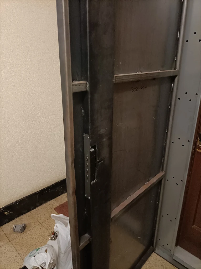 Detalle de la estructura interna y cerradura durante la instalación de una puerta de seguridad blindada
