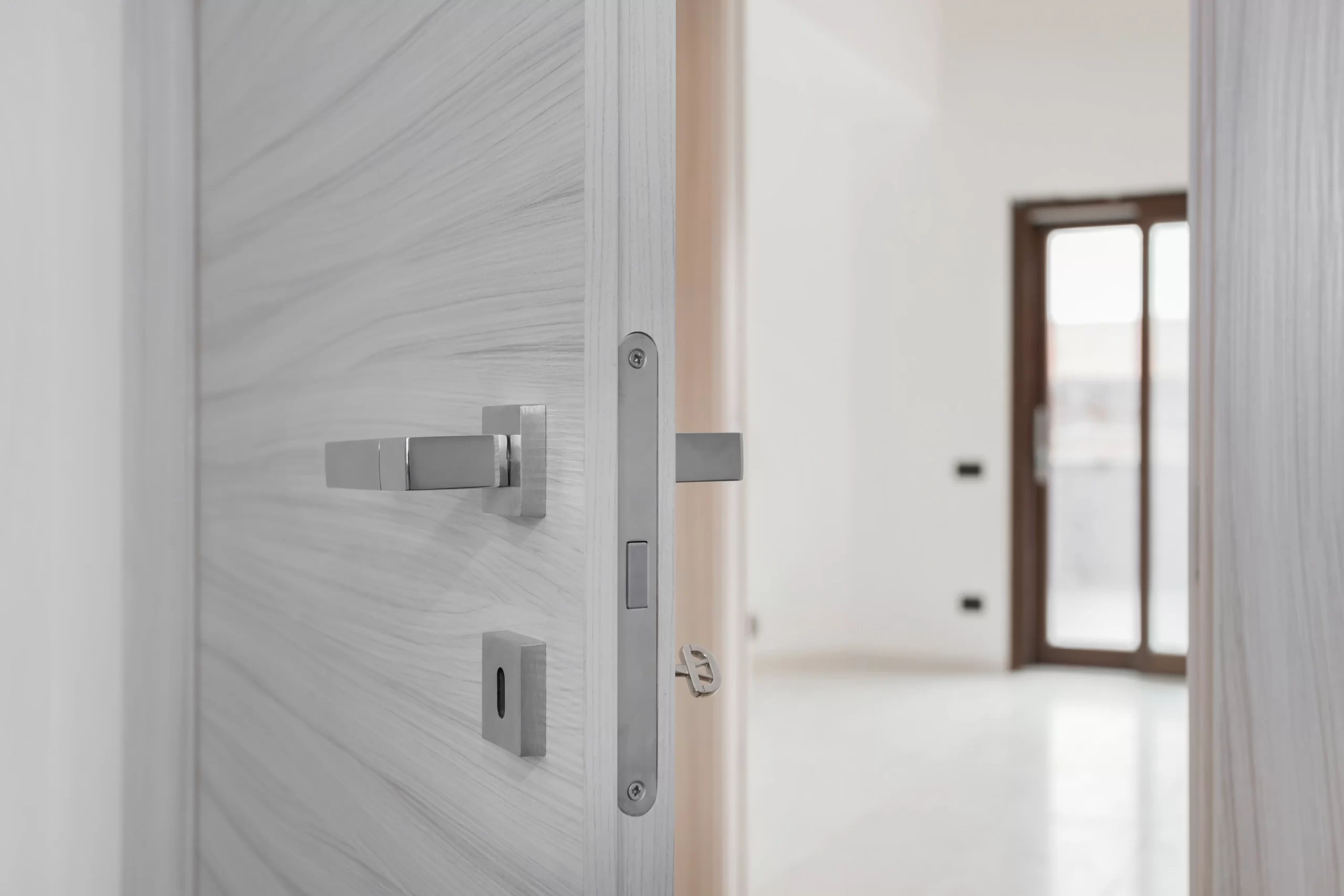 Montaje de puerta de paso con veta horizontal grisácea y picaporte de diseño moderno en vivienda reformada