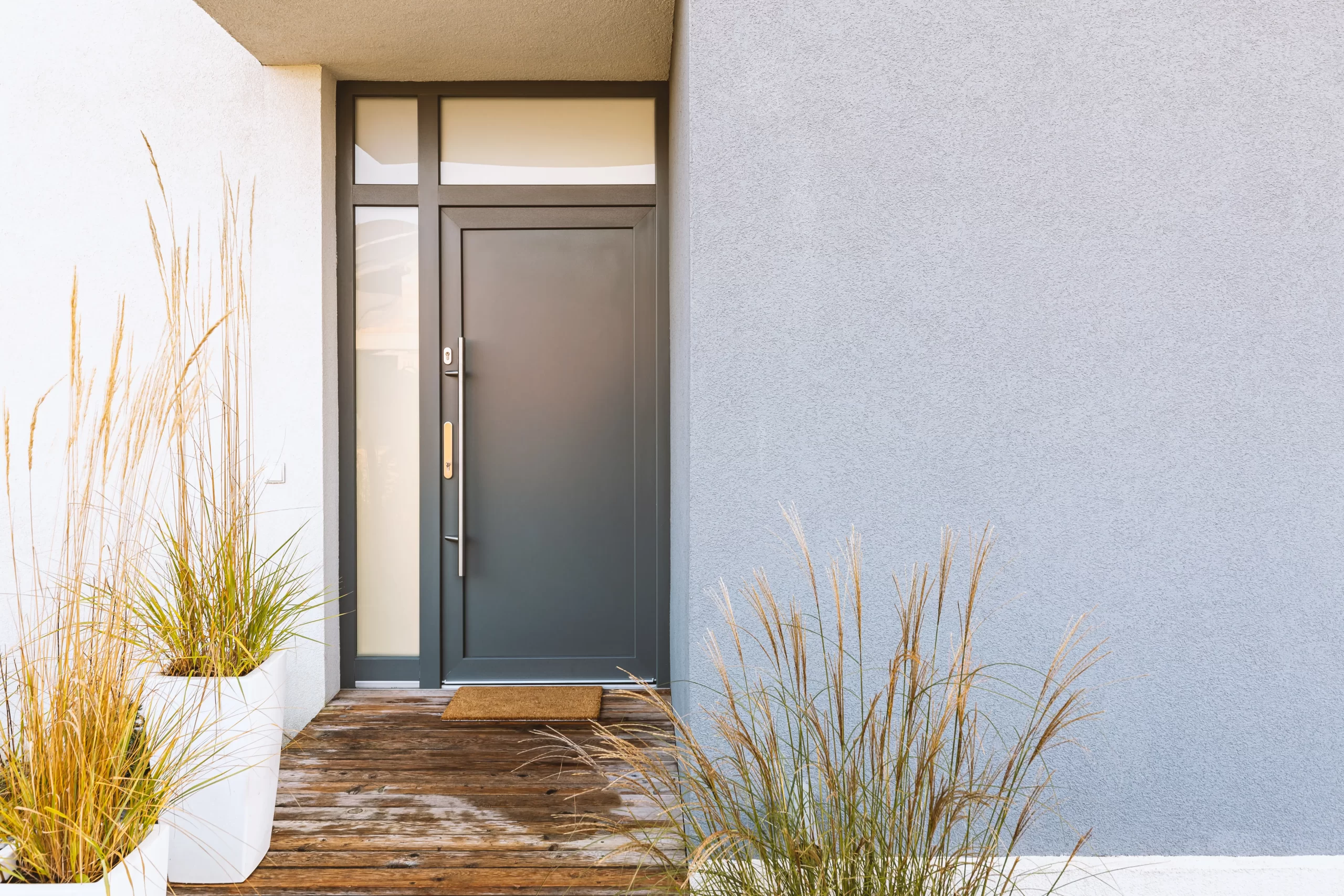 Puerta de aluminio gris moderna en entrada de casa con necesidad de ajuste y mantenimiento de herrajes
