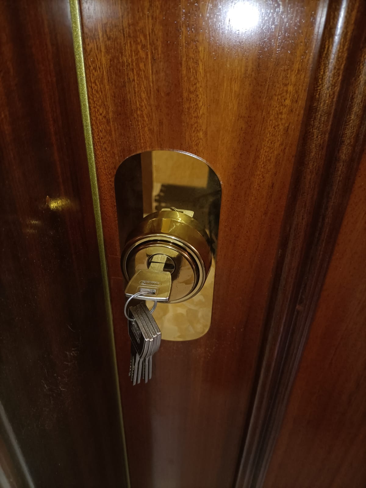 Bombín dorado con llaves insertado en puerta madera
