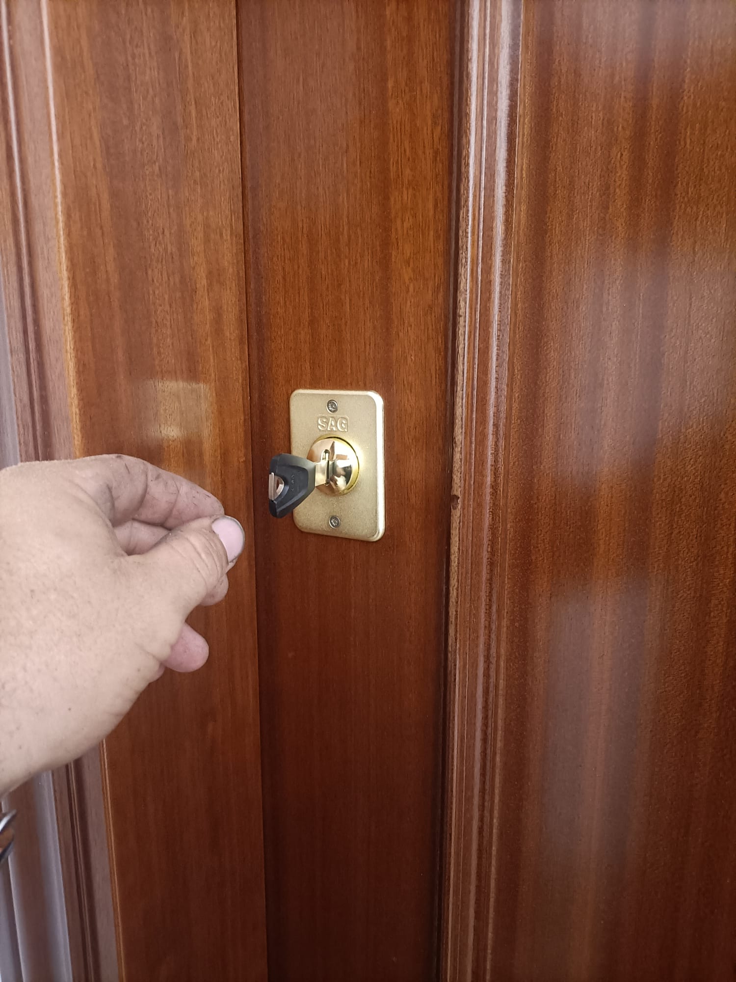 Mano insertando llave en bombín SAG dorado